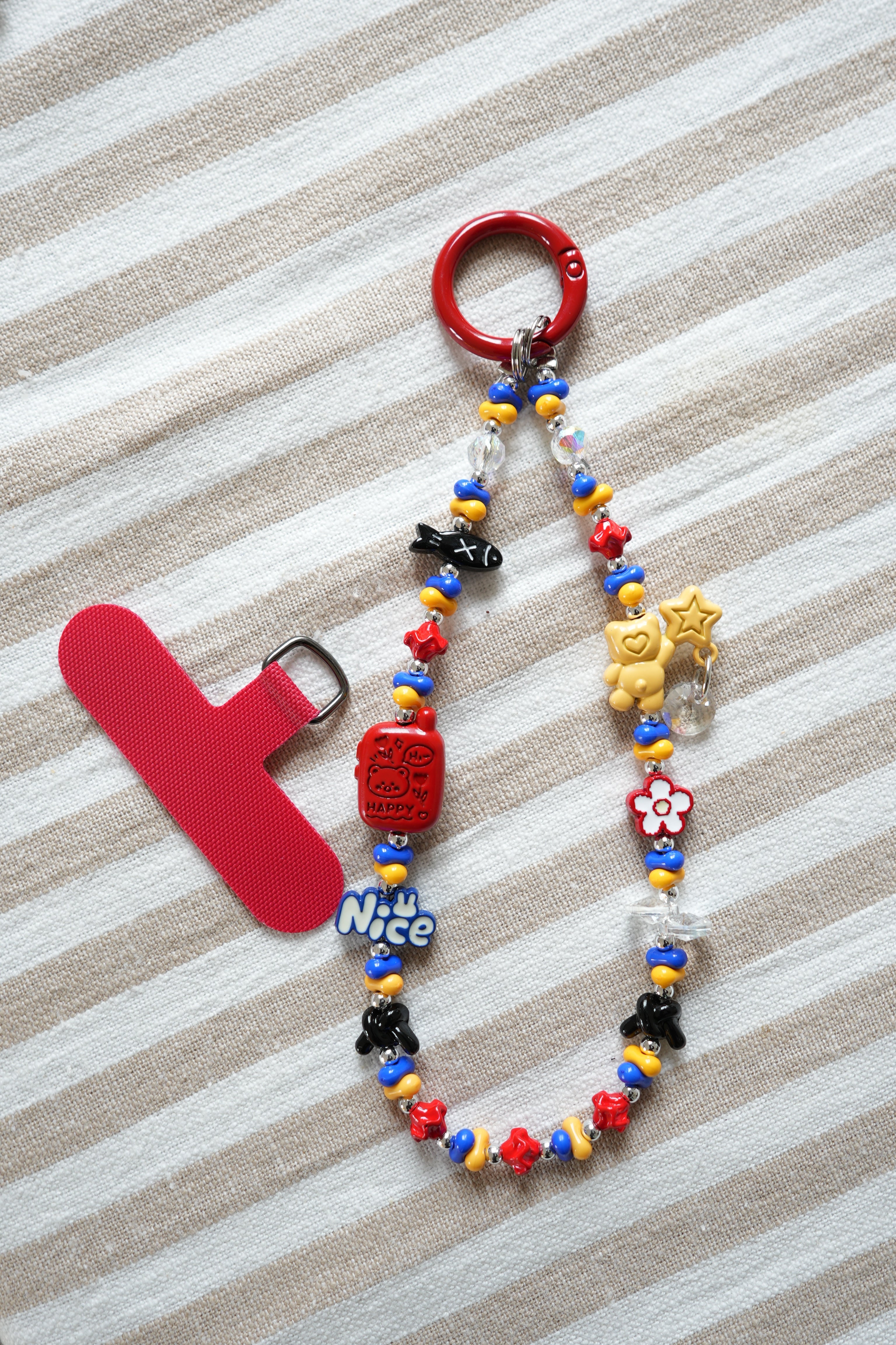 Colorful beaded keychain with red clip on striped fabric background