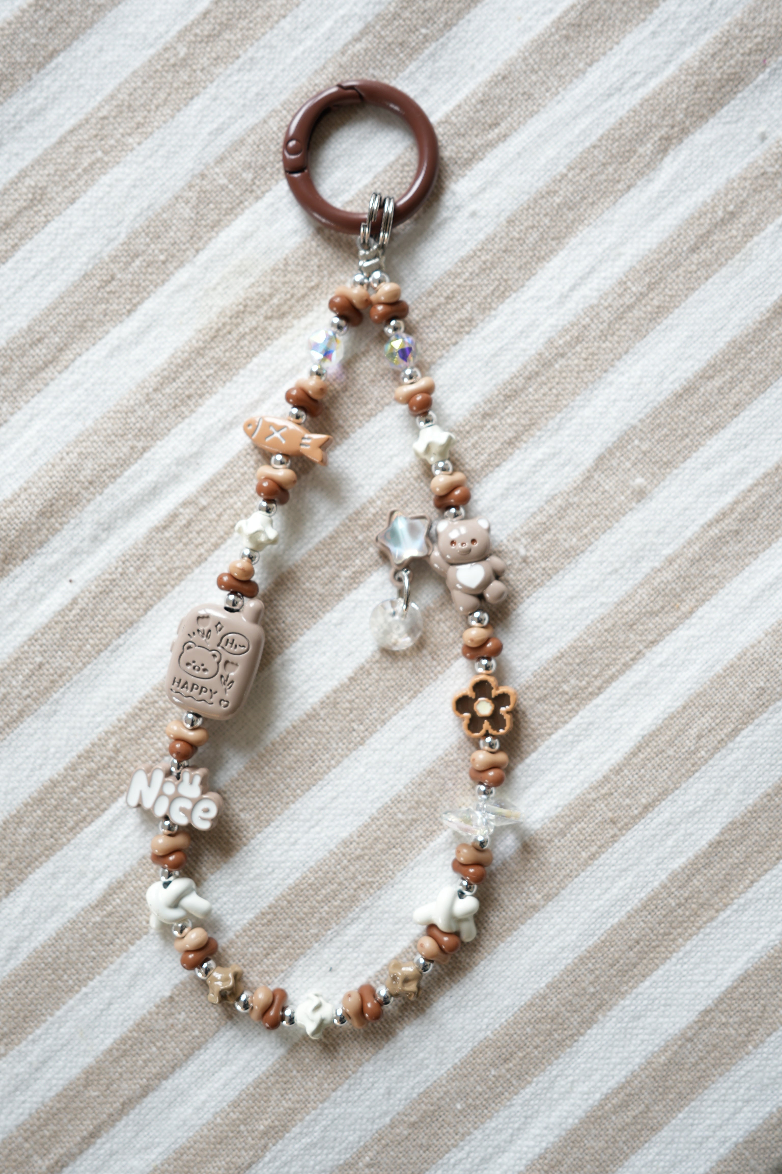 Beaded keychain with decorative elements on a striped fabric background